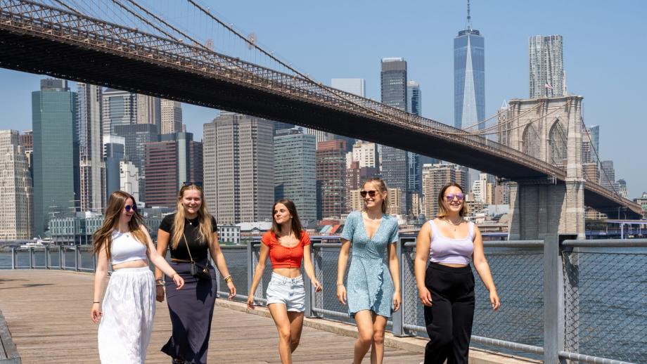 Gruppe på fem au pairs går ved Brooklyn Bridge